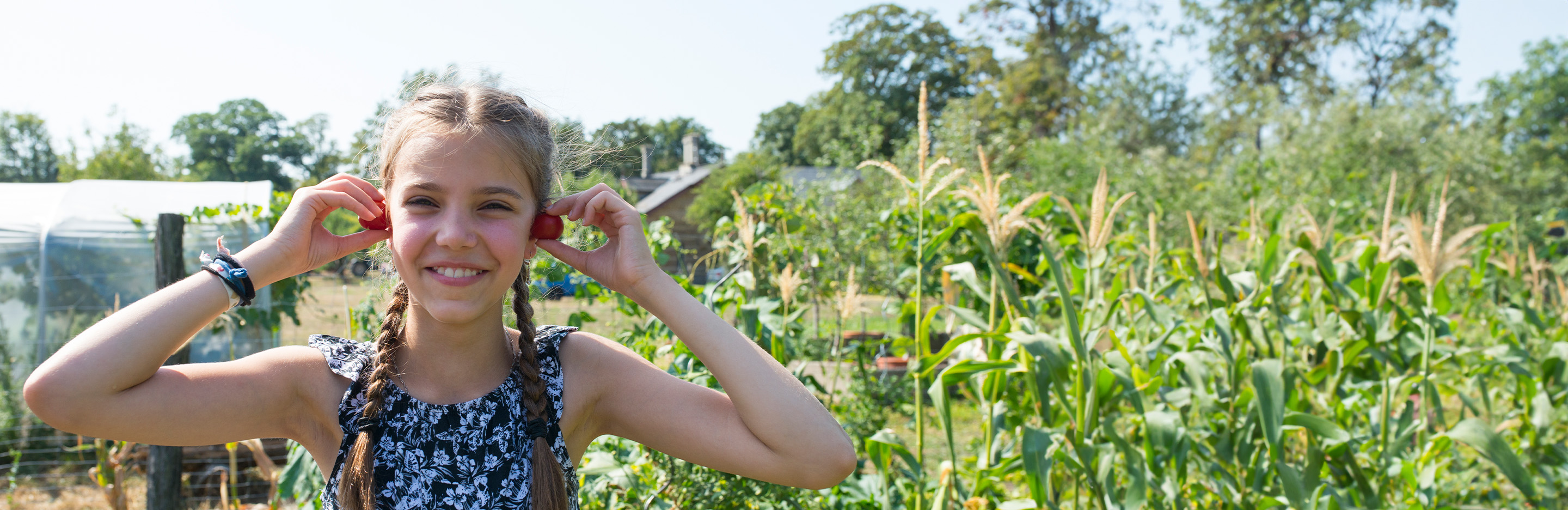 Junges Mädchen hält sich Tomaten an die Ohren