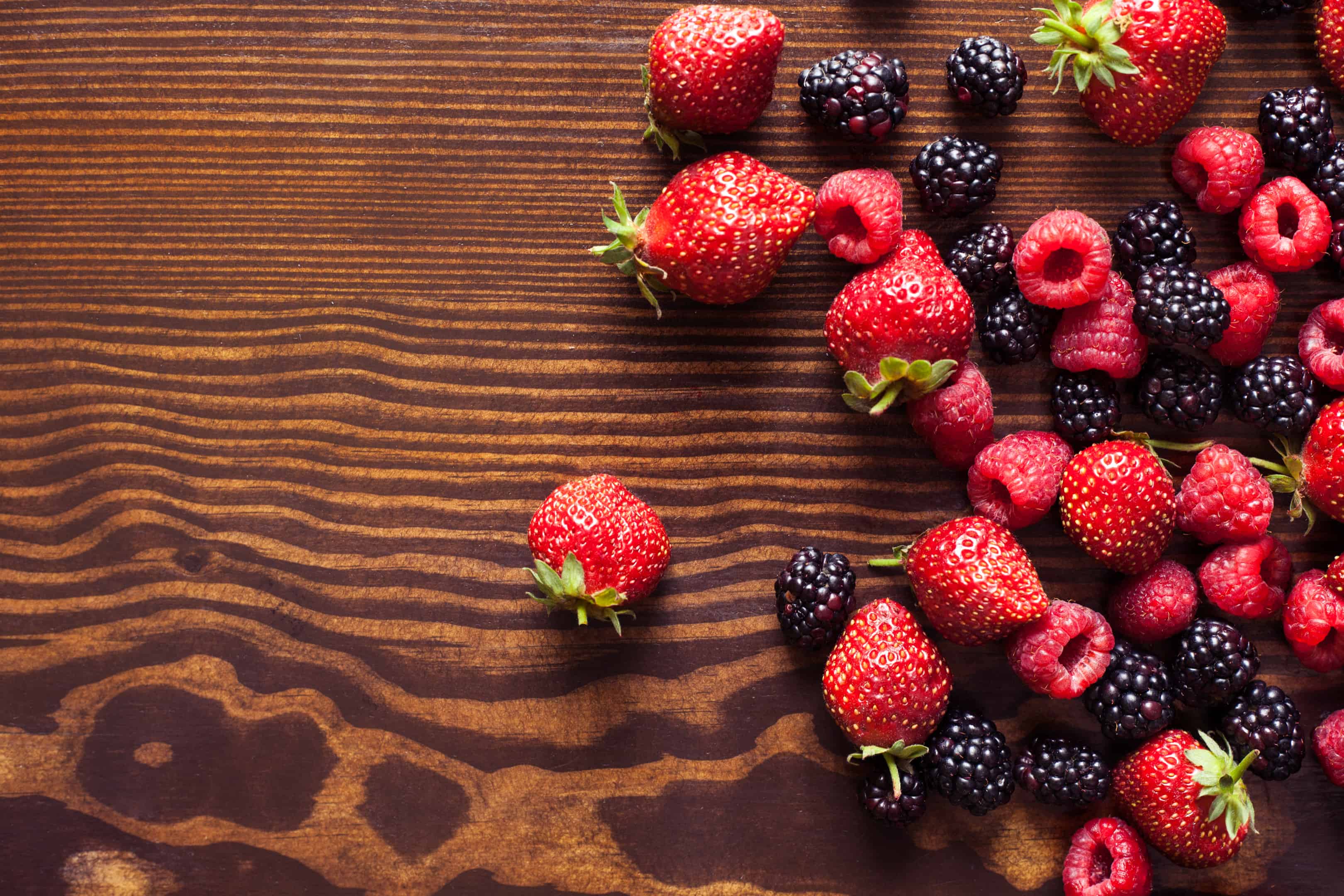 Strawberries, raspberries and blackberries on a wooden table