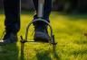 Un jardinier en train d’aérer la pelouse de son jardin avec un outil manuel.