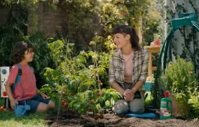 Mutter und Kind im Garten zwischen Tomatenpflanzen