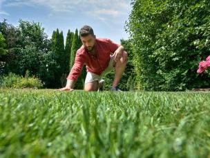 Mann streicht über perfekten Rasen im Garten