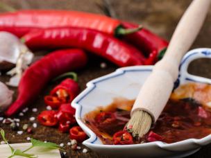 Marinade in sauce wit brush next to garlic and chillies