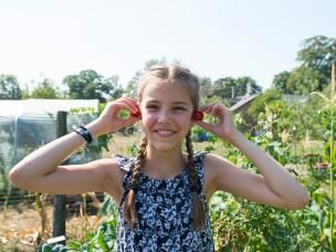Junges Mädchen hält sich Tomaten an die Ohren