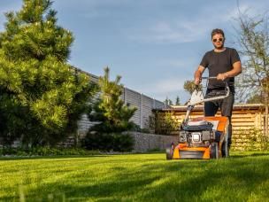 A man mowing a lawn with a lawn mower, showing the difference between overgrown grass and freshly cut grass