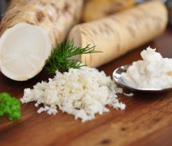 Sections of harvested horseradish root and grated horseradish on a wooden table