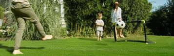 Kinder spielen Fußball im Garten