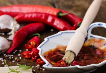 Marinade in saucer with brush, chillies and garlic on the side