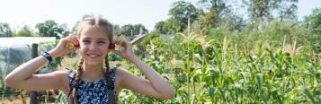 Junges Mädchen hält sich Tomaten an die Ohren