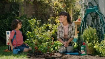 Mutter und Kind im Garten zwischen Tomatenpflanzen